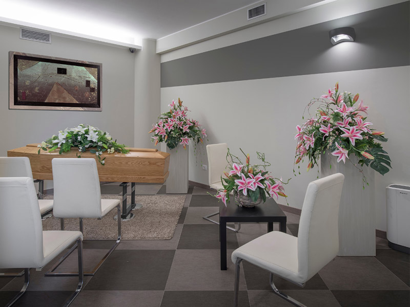 Sala del commiato con sedute e gigli rosa
